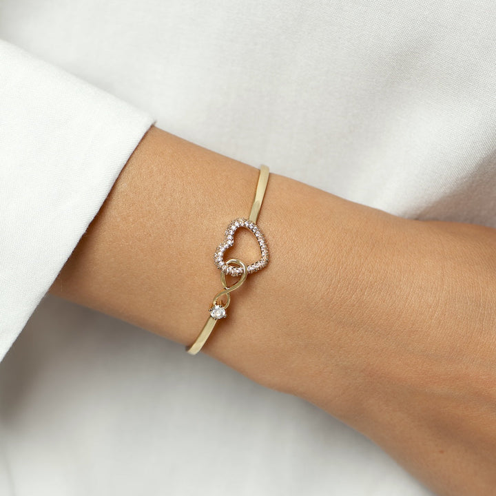 Bracciale romantico in oro con cuore di zirconi e nodo infinito.

